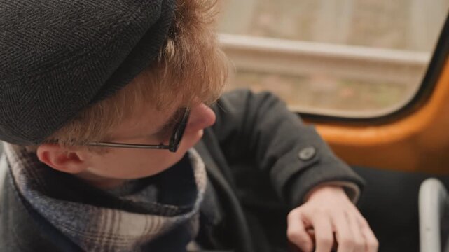 Teenager silently watches during bus ride outside. Young individual attentively scans scene beyond window. Juvenile remains quiet and focused while viewing surroundings from bus window