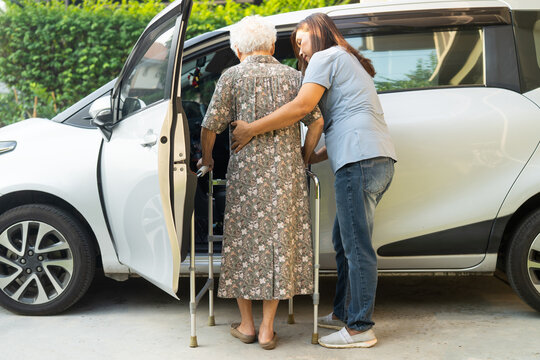 Caregiver help Asian elderly woman disability patient get into car.
