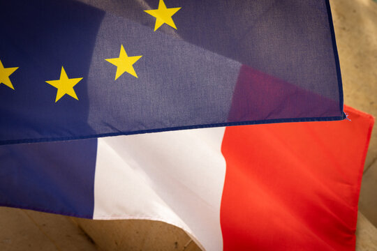 Le drapeau europ&eacute;en et le drapeau fran&ccedil;ais se croisent dans le vent, tissant une alliance visuelle entre identit&eacute; nationale et engagement collectif.