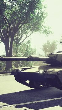 A tank is parked on a city street surrounded by green trees. The scene shows bright daylight and a clear view of the urban area. The tank is in a defensive position.