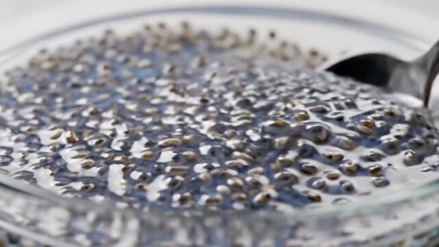Chia seed soaked water glass bowl with spoon showing gel texture hydration superfood rich fiber omega 3 fatty acid milk pouring into glass bowl filled chia seed healthy superfood breakfast ingredient