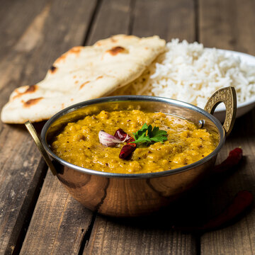 A steaming bowl of Dal on a rustic table, creamy lentil curry with turmeric golden color, topped with cumin tempering
