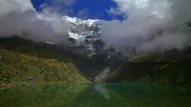 Peru's Laguna Humantay glacial Lake Humantay rocky shoreline Peruvian Andes Mount Humantay Peru nature landscape view snow covered peaks fog cloud layer morning sunny cloudy tourist destination