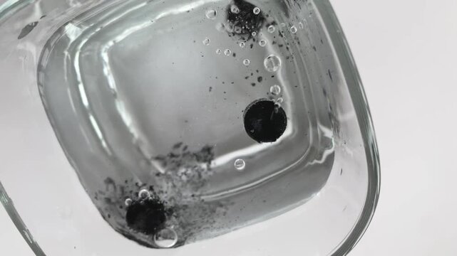 Effervescent tablet. Black medicinal tablets. Water. Glass. slow motion video. High quality footage 4k