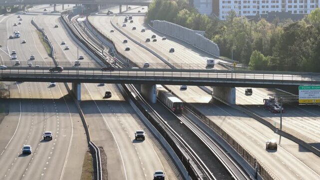 Aerial establishing shot of Reston, Virginia highway traffic with metro train in center median during sunny spring sunset. Busy commuter transportation scene near Washington DC USA.