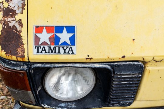 Nonthaburi, Thailand - 23 April 2026: Closeup of Tamiya logo sticker above headlight of on weathered yellow vintage van car front with cracked paint and heavy rust. showing authentic patina and wear.