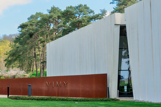 Modern concrete museum at Vimy Memorial in France, minimalist architecture set in green landscape under blue sky, symbol of remembrance and history.