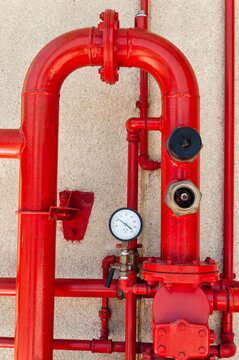 Red Industrial Fire Sprinkler System with Pipes and Gauges Against a Wall
