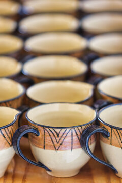 Handcrafted Ceramic Mugs with Tribal Geometric Patterns in Rows on a wooden surface.