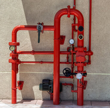 Red Industrial Fire Sprinkler System with Pipes and Gauges Against a Wall