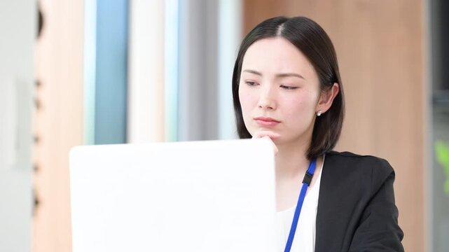 パソコンの前で真剣な表情で考える悩むデスクワーク業務に取り組む女性会社員　困ったな～の動画