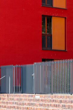 Minimal urban architecture of red building facade with windows and fence using strong color and clean wall geometry in modern design