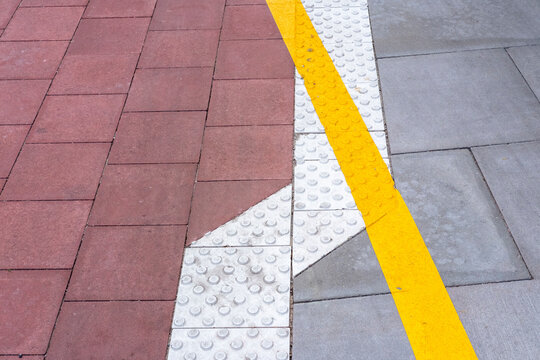 Abstract urban sidewalk with pavement tiles texture and pattern showing yellow line marking on a clean modern geometric street surface