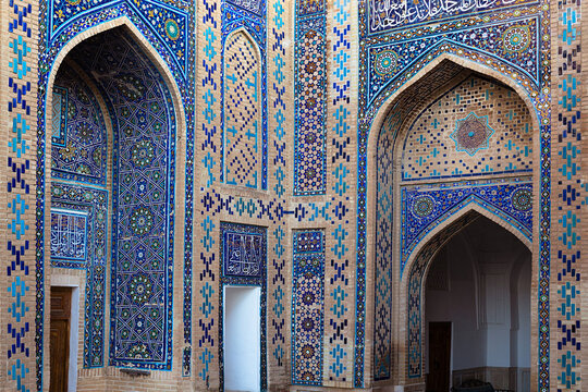 Ornate tilework facade at Shah-i-Zinda necropolis in Samarkand featuring blue mosaic arches and geometric patterns. Ideal for travel, heritage, and architectural publications.
