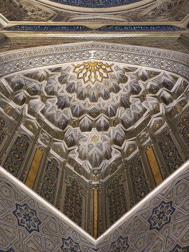 Muqarnas vault with gold and blue tile decoration inside a mausoleum at Shah-i-Zinda necropolis in Samarkand. Ideal for travel publications, heritage content, and architectural studies.