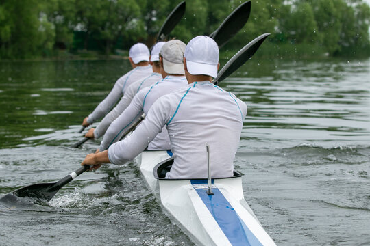 Close-up four athletes kayakers paddling on open water