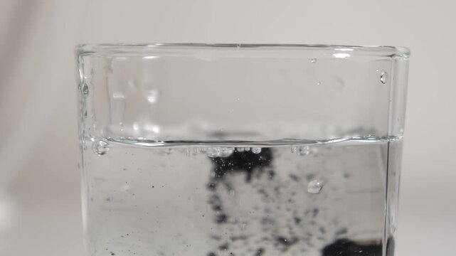 Medicinal pills. Glass of water. Black medical pills. Slow motion. High quality 4k footage