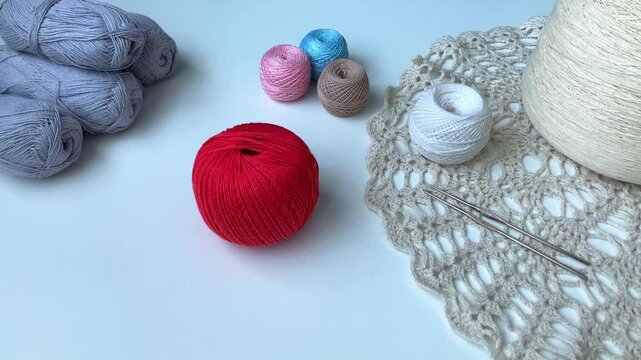 A woman's hand gently picks up a ball of thread. Hobby, crochet. Tangles, crochet hooks, a white table. Peace from the simplest things