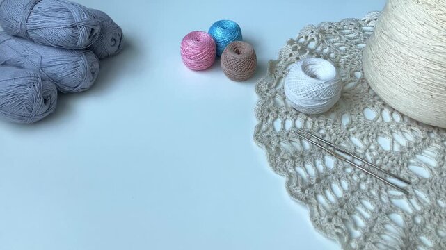 A woman's hand gently places a ball of thread on a white table. A cozy hobby at home. Tangles, hooks, crocheting. A sense of order and inner balance, the pleasure of simple, understandable actions