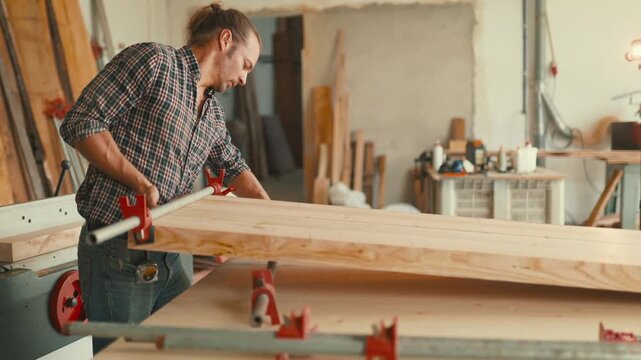 Carpenter clamping and gluing wooden planks together