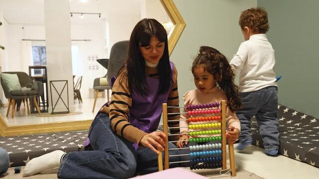 Teacher helping children learn with abacus in nursery school playroom