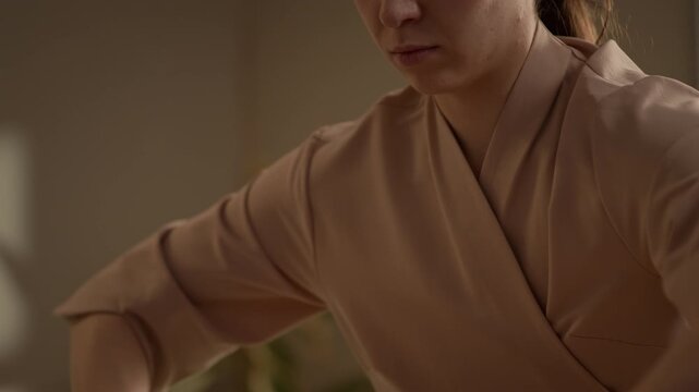 Tilt down closeup shot of female massage professional using oil while massaging male client back with strong hands during therapeutic wellness session in cozy treatment room