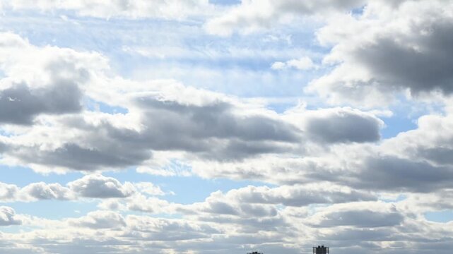 Different cloud patterns move across the sky above an open field in a rural area during the afternoon. The light changes as clouds shift, creating different views