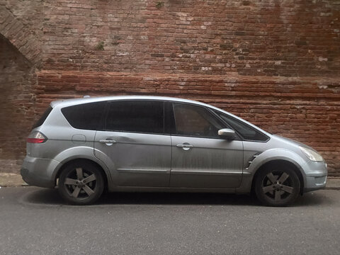 Ford S Max minivan parked along a weathered brick wall in an urban setting during an overcast day