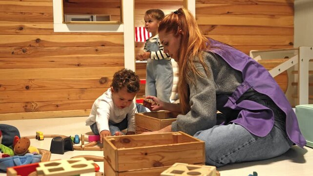 Nursery school teacher playing wooden toys with toddler boy
