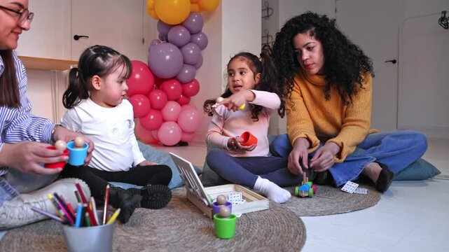 Kindergarten teachers playing educational games with toddler girls