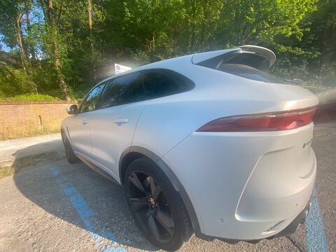 Jaguar F Pace SVR parked on asphalt with sunlight highlighting the luxury matte white sports utility vehicle