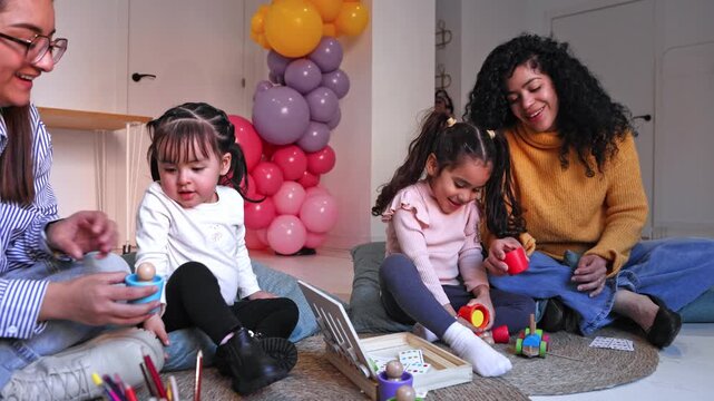 Female teachers playing educational games with toddler girls