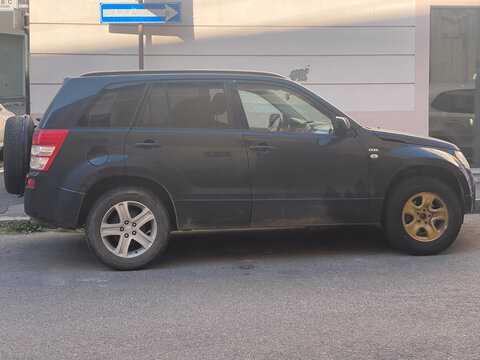 Suzuki Grand Vitara DDiS parked roadside, rugged black SUV with distinctive gold front wheel rim, urban street profile