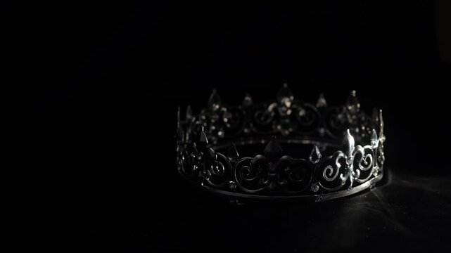 Elegant vintage gold crown with gemstones on black background, luxury brand and premium concept. Refined vintage gold crown decorated with diamonds, and crystals placed on a dark fabric background