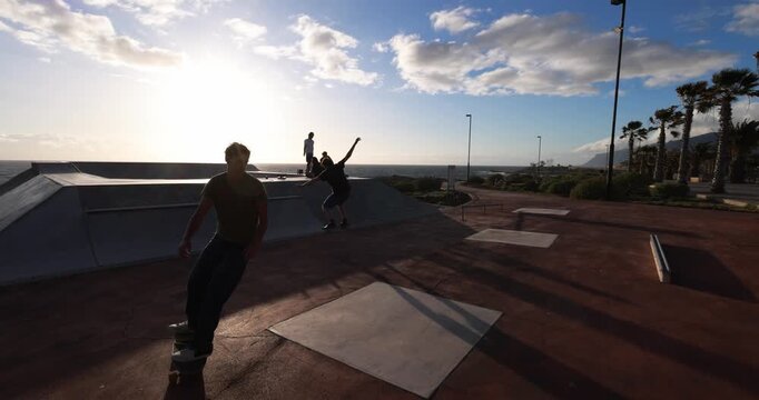 Young people having fun at skateboard park outdoor during sunset time - Summer lifestyle, teenager boys and extreme sport concept