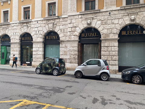 Smart Fortwo microcars parked on a Rome street in front of BNL bank building, showing urban lifestyle