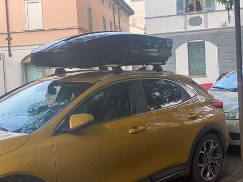 Kia XCeed crossover with Thule roof top cargo box parked on street, ready for adventure and travel