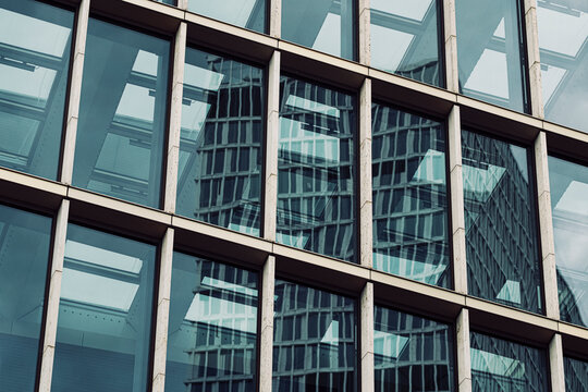 Glass building exterior detail with modern architecture facade windows reflections and abstract geometry grid texture creating a sleek pattern