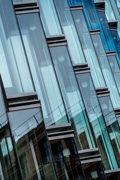 Diagonal glass building exterior detail with modern architecture facade windows and abstract pattern reflections geometry in contemporary urban design