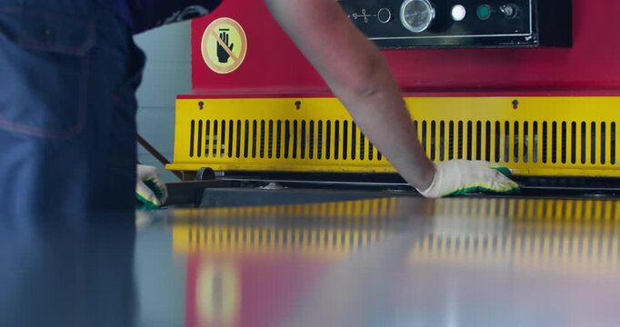 Hydraulic guillotine shear working. Hand of cutting machine operator. Raise production efficiency