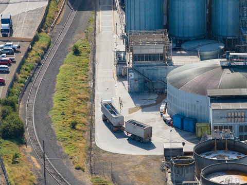 Aerial view of a semitrailer leaving a storage facility full of large storage tanks