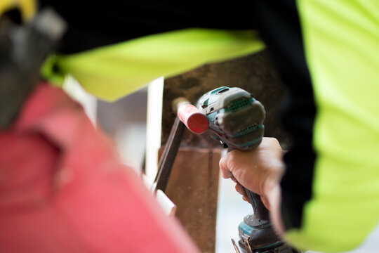 A tradesman drills into a wooden beam.