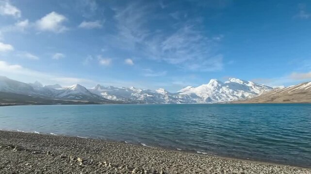 Stunning  panoramic view of the turquoise Sapukonglagu glacier lake and unique triangular snow peaks under a blue sky in Tibet China.
