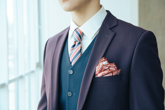 stylish man in purple jacket standing near window, groom before wedding, tie around neck and handkerchief in jacket pocket