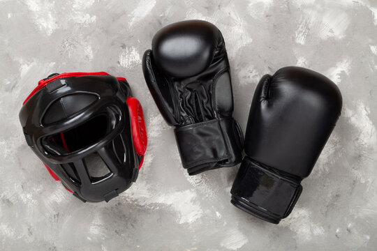 Boxing helmet and gloves on concrete background, top view.