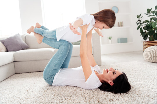 Mother playing with daughter on the living room carpet, joyful family bonding and playful parent-child moment at home