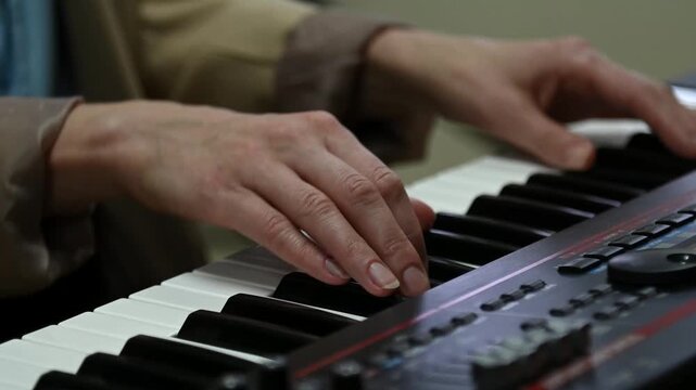 female pianist hands on black and white synthesizer keyboard, close-up view, young woman playing piano, professional musician