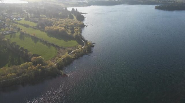 Cinematic 4K aerial drone footage capturing the vast expanse of Store Stokkavannet (Lake Stokkavannet) and its surrounding residential landscape in Stavanger, Rogaland, Norway. The scene features clea