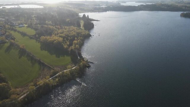 Cinematic 4K aerial drone footage capturing the vast expanse of Store Stokkavannet (Lake Stokkavannet) and its surrounding residential landscape in Stavanger, Rogaland, Norway. The scene features clea