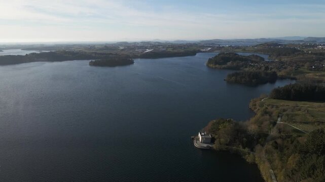Cinematic 4K aerial drone footage capturing the vast expanse of Store Stokkavannet (Lake Stokkavannet) and its surrounding residential landscape in Stavanger, Rogaland, Norway. The scene features clea